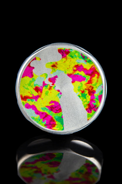 Colorful glass cannabis oil rig dome with abstract pink, green, and blue swirls and a white silhouette, reflected on a black surface.