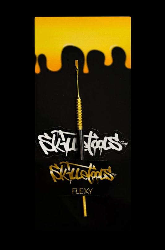 A close-up, angled view of the Skilletools Gold Series Dab Tools, featuring a sleek, gold-toned metal tip against a dark background.