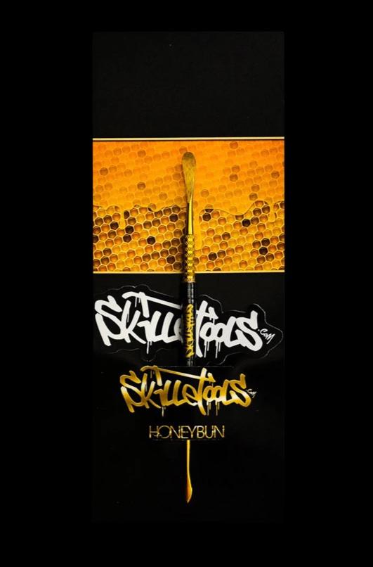 A close-up, angled view of the Skilletools Gold Series Dab Tools against a dark, textured background.