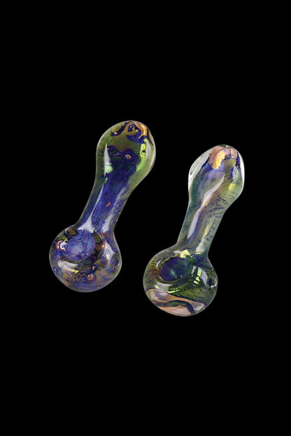 A close-up, angled view of the Spattered Fumed Hand Pipe, showcasing its colorful, glass construction against a dark background.