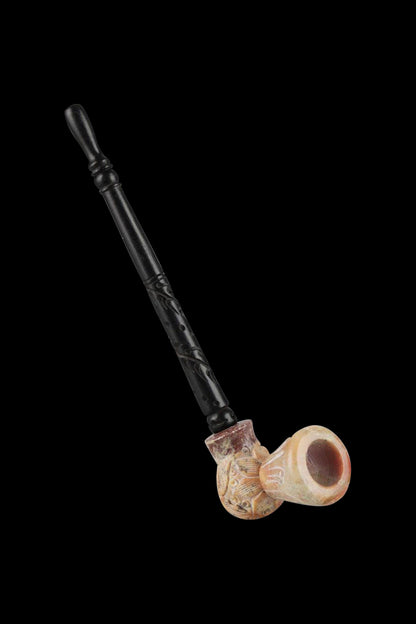 A detailed side view of the Stone Carved Pipe with Wood Stem, showcasing the ornate stone bowl and dark wooden stem.