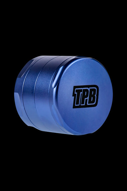 Blue metal cannabis grinder with “TPB” logo against a black background.