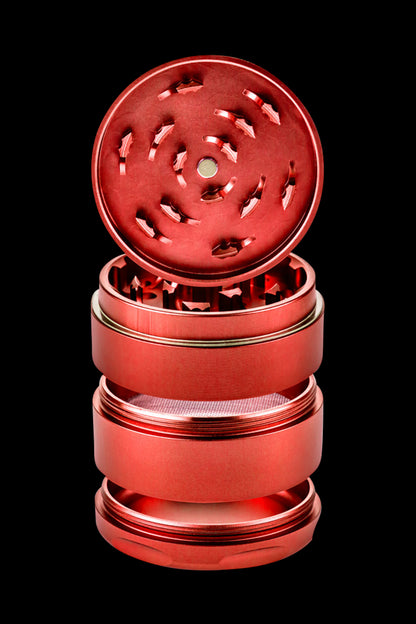 Red four-piece metal cannabis grinder, disassembled.