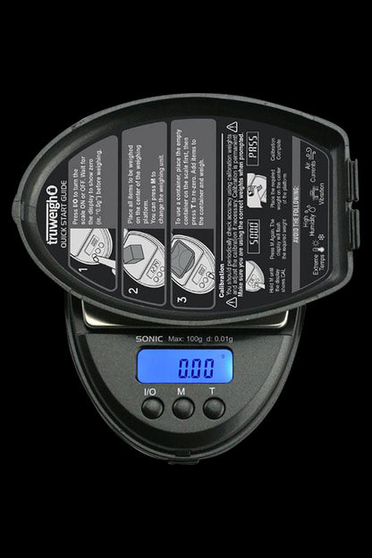 Close-up of the Truweigh Sonic Digital Mini Scale displaying a zero reading, with instructional text visible on its surface.