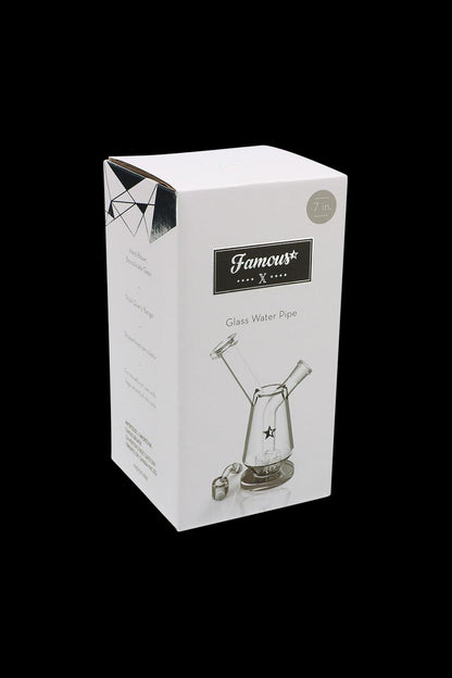 Three-quarter view of the boxed Famous X Drip Dab Rig on a black background, showing the white packaging and product illustration.