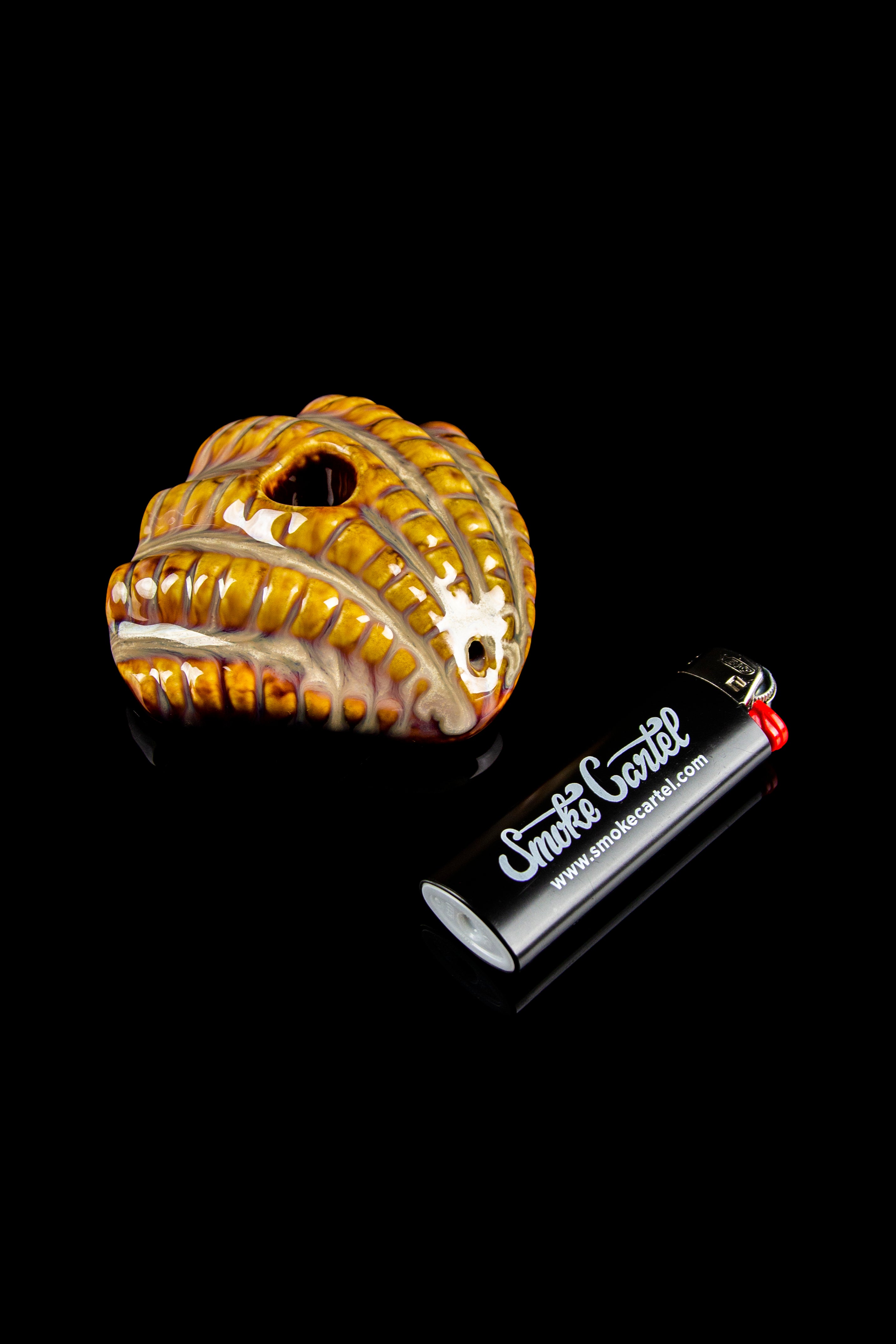 A close-up shot of the Art of Smoke Clamshell Pipe, showcasing its textured, shell-like design against a dark background.