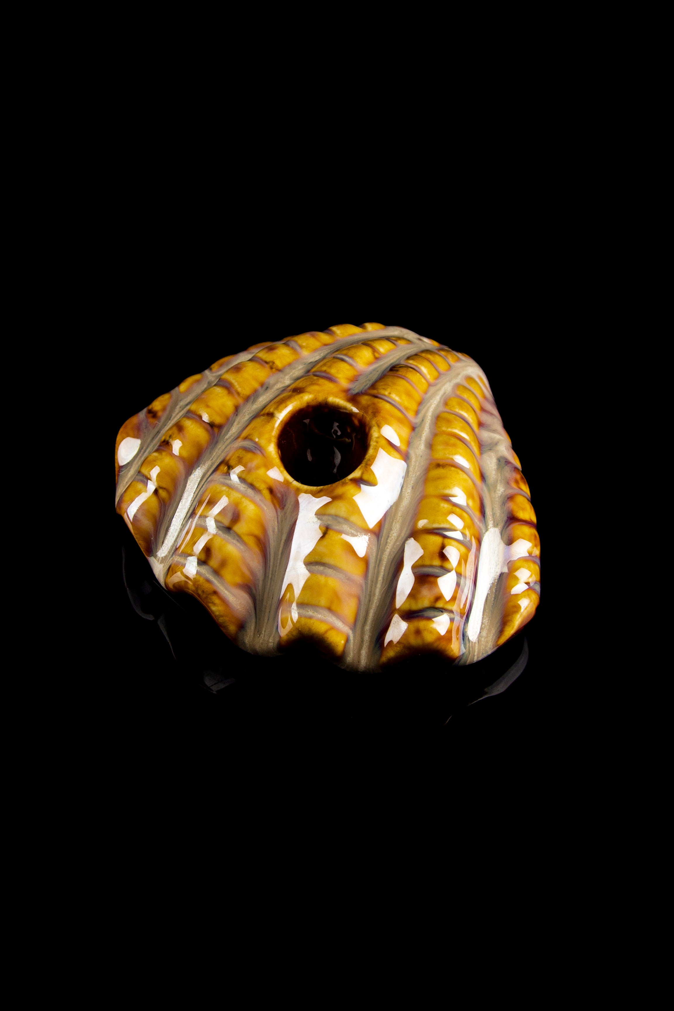 A close-up, angled view of the Art of Smoke Clamshell Pipe, showcasing its textured, brown and cream-colored design.