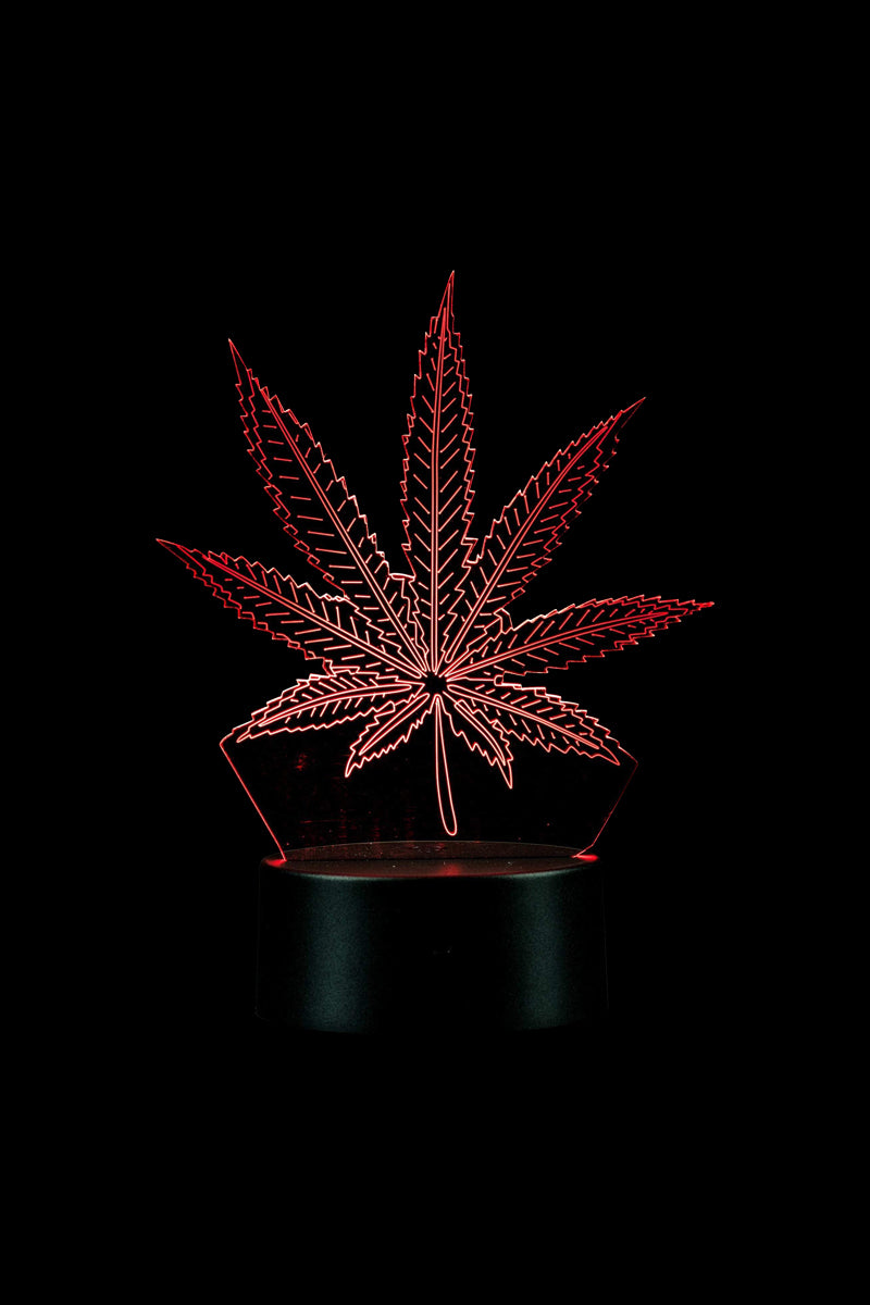 A low-angle view of the 3D Cannabis Leaf Lamp, its illuminated green leaf casting a soft glow against a dark background.