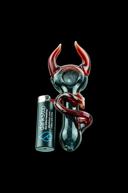 A detailed studio shot of the Little Devil Hand Pipe, showcasing its sculpted, dark-colored design against a plain black backdrop.