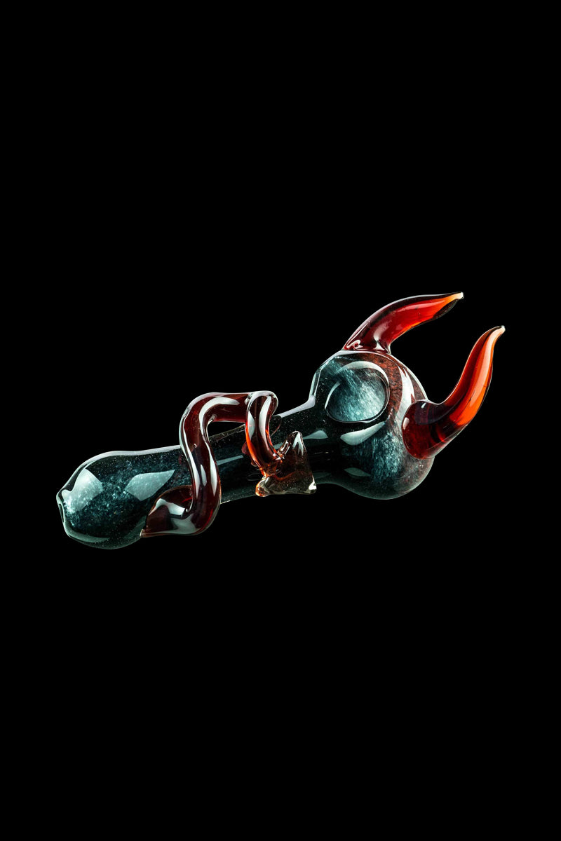 A detailed side view of the Little Devil Hand Pipe, featuring a vibrant red and dark glass design.