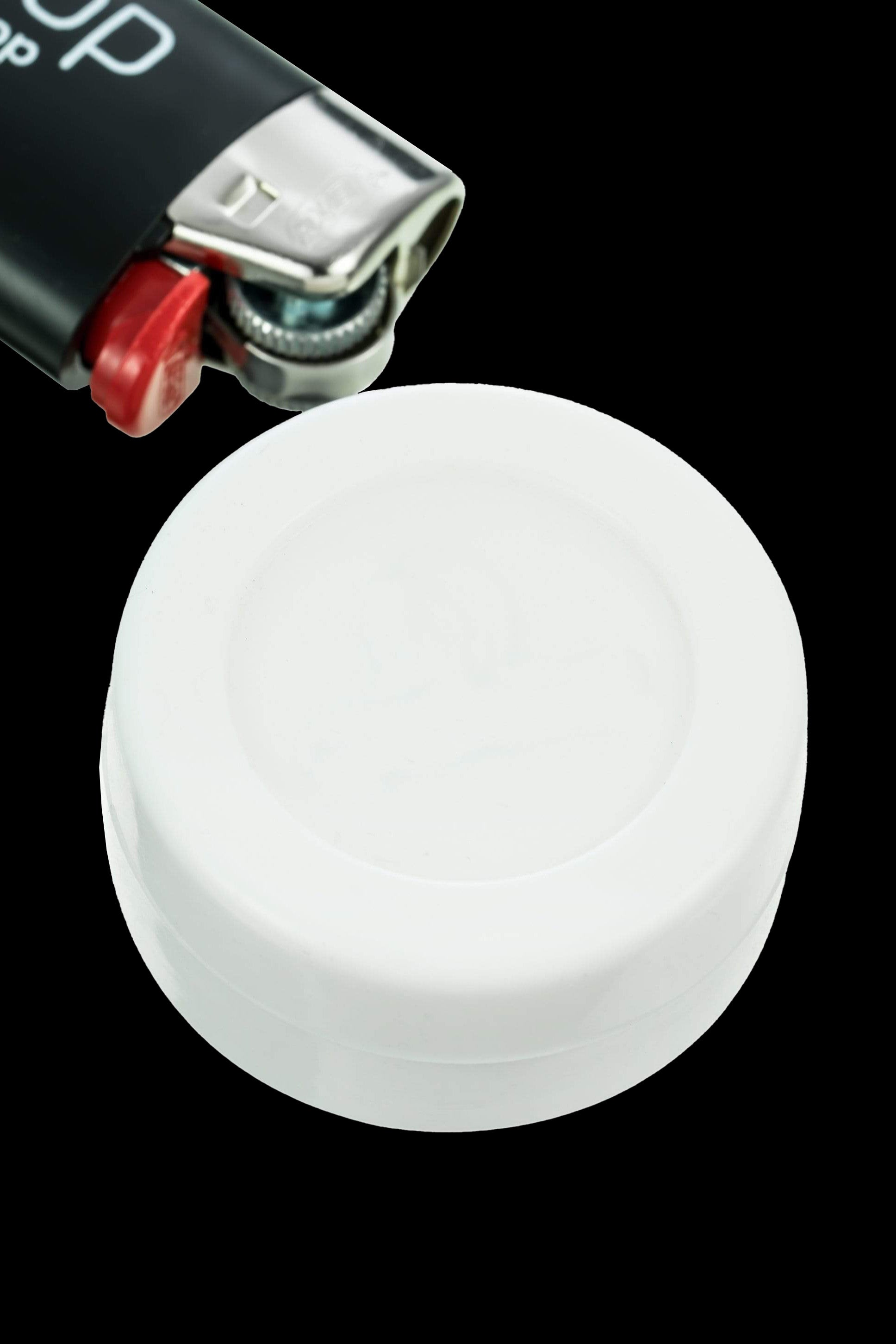 White silicone cap for a dab rig, with a lighter partially visible above."