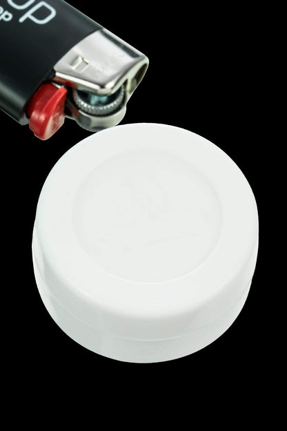 White silicone cap for a dab rig, with a lighter partially visible above."