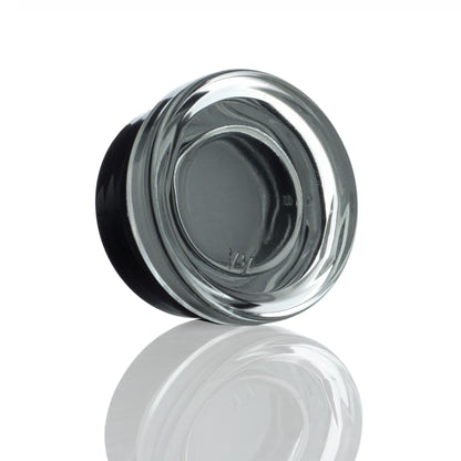 A close-up, angled view of the Dip Devices 9mL Glass Container, reflecting on a smooth surface.