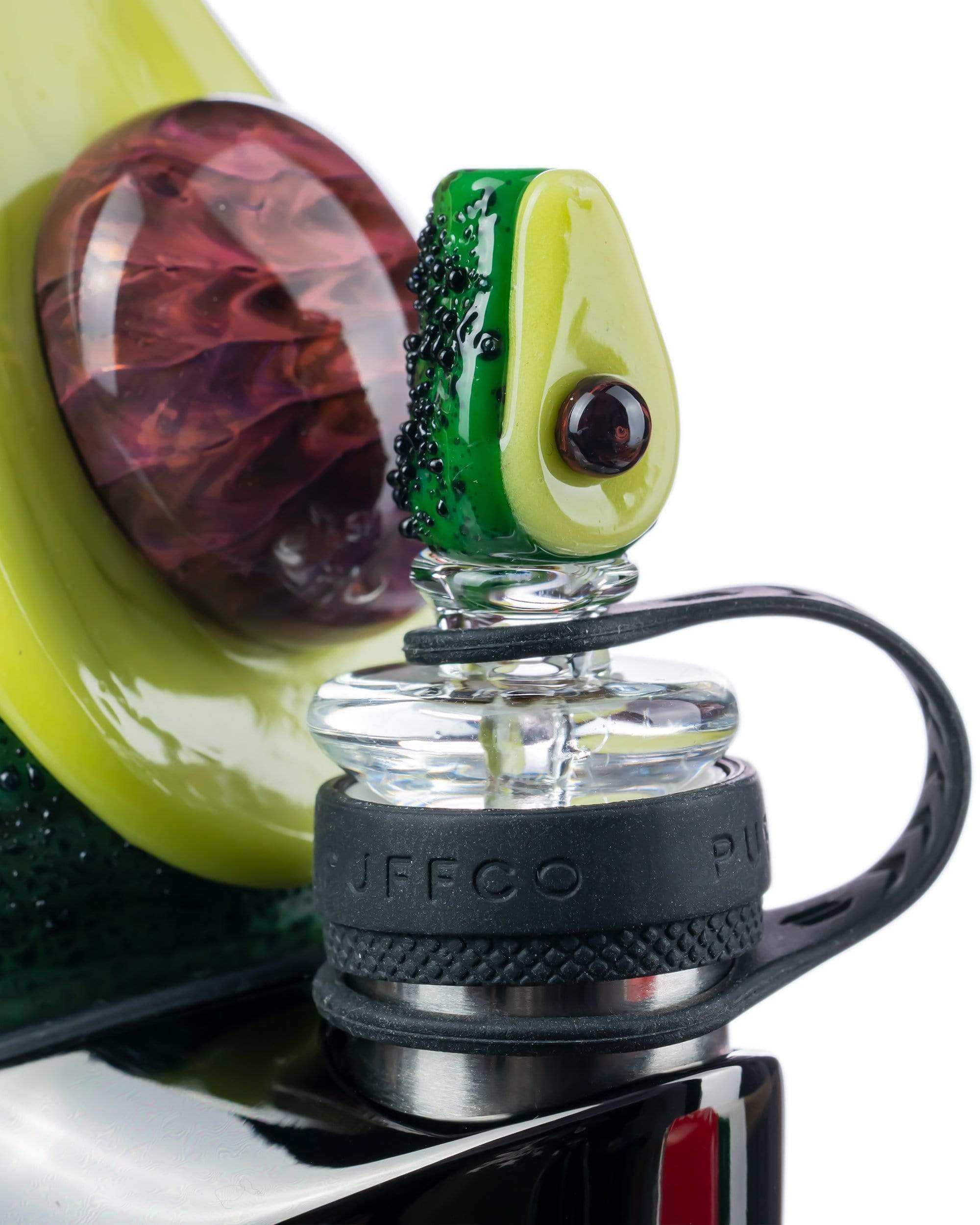 Close-up view of the Empire Glassworks Avocadope Carb Cap for Puffco Peak, showcasing its green, sculpted design against a blurred background.