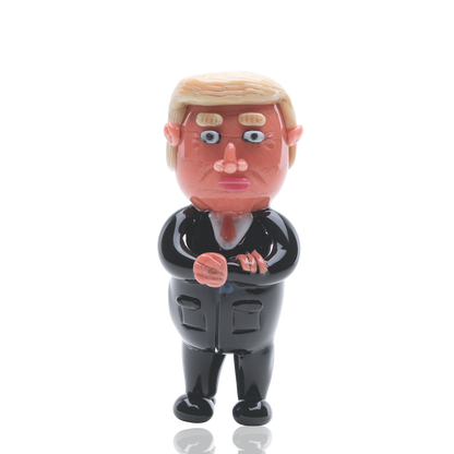 Front view of the Empire Glassworks “Agent Orange” Trump hand pipe, a sculpted, orange-toned figurine presented on a plain white background.