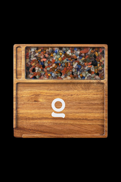 Wooden cannabis accessory box filled with colorful crystal-like pieces, featuring a circular logo on the front.