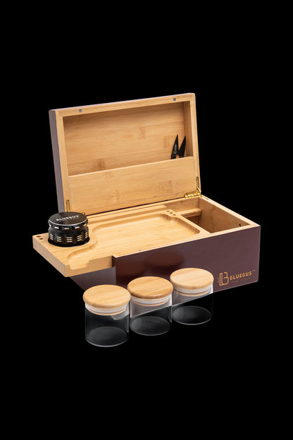 Wooden cannabis storage box with grinder and jars on a dark background.