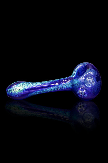 Blue glass smoking pipe with glitter effect, reflecting on a black surface.