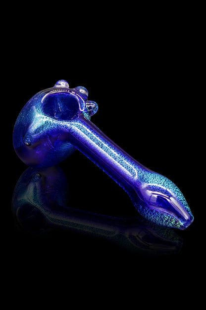 Blue glass pipe with glitter flecks, reflecting on a dark surface.