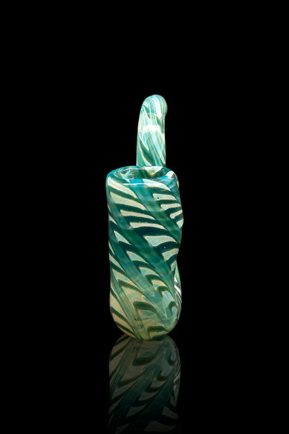 Green and teal swirled glass dab rig with a looped handle, reflected on a dark surface.