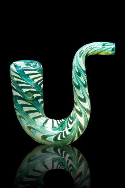 Hand-blown glass cannabis pipe with swirling green and cream patterns, reflected on a black surface.