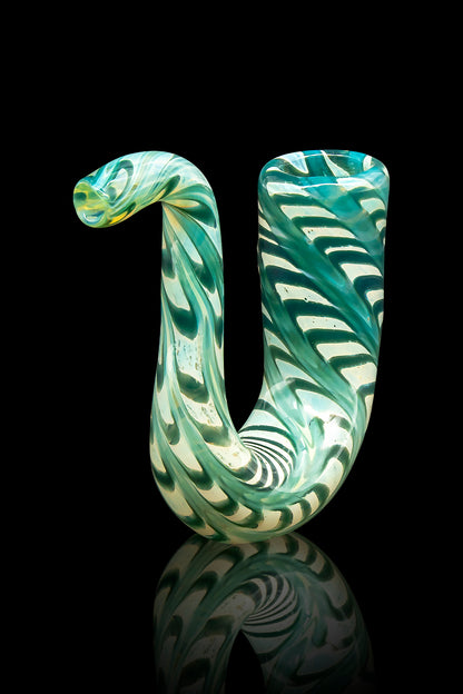 Hand-blown glass cannabis water pipe with swirling teal and cream patterns, reflected on a black surface.