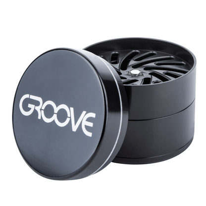 An open Aerospaced Groove 4-Piece Aluminum Grinder shown at a slight angle, revealing its multi-tiered interior.