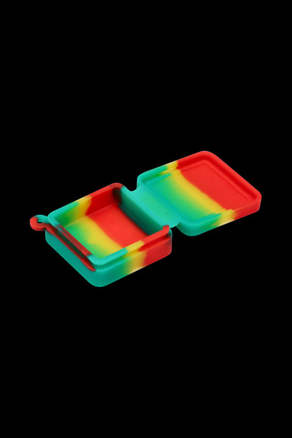 Angled top-down view of the Silicone Square Keychain Stash Container open to show its red, yellow, and green swirled interior against a black background