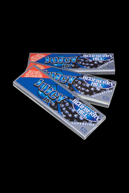 A close-up shot of the packaging for Juicy Jay's Superfine 1-1/4" Flavored Rolling Papers, displaying colorful branding and text on a dark background.