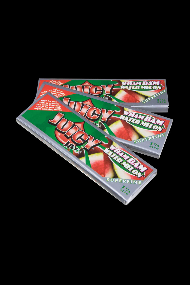 Close-up of Juicy Jay's Superfine 1-1/4" flavored rolling papers stacked on a dark surface, showing colorful patterned designs.