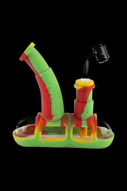 A close-up of the Ooze Steamboat Silicone Bubbler Boat Bong, displaying its colorful, boat-shaped design against a black background.