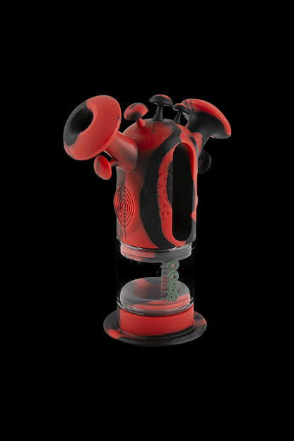 A studio shot showcases the Ooze "Trip" Silicone Bubbler, a compact, red water pipe presented against a black background.