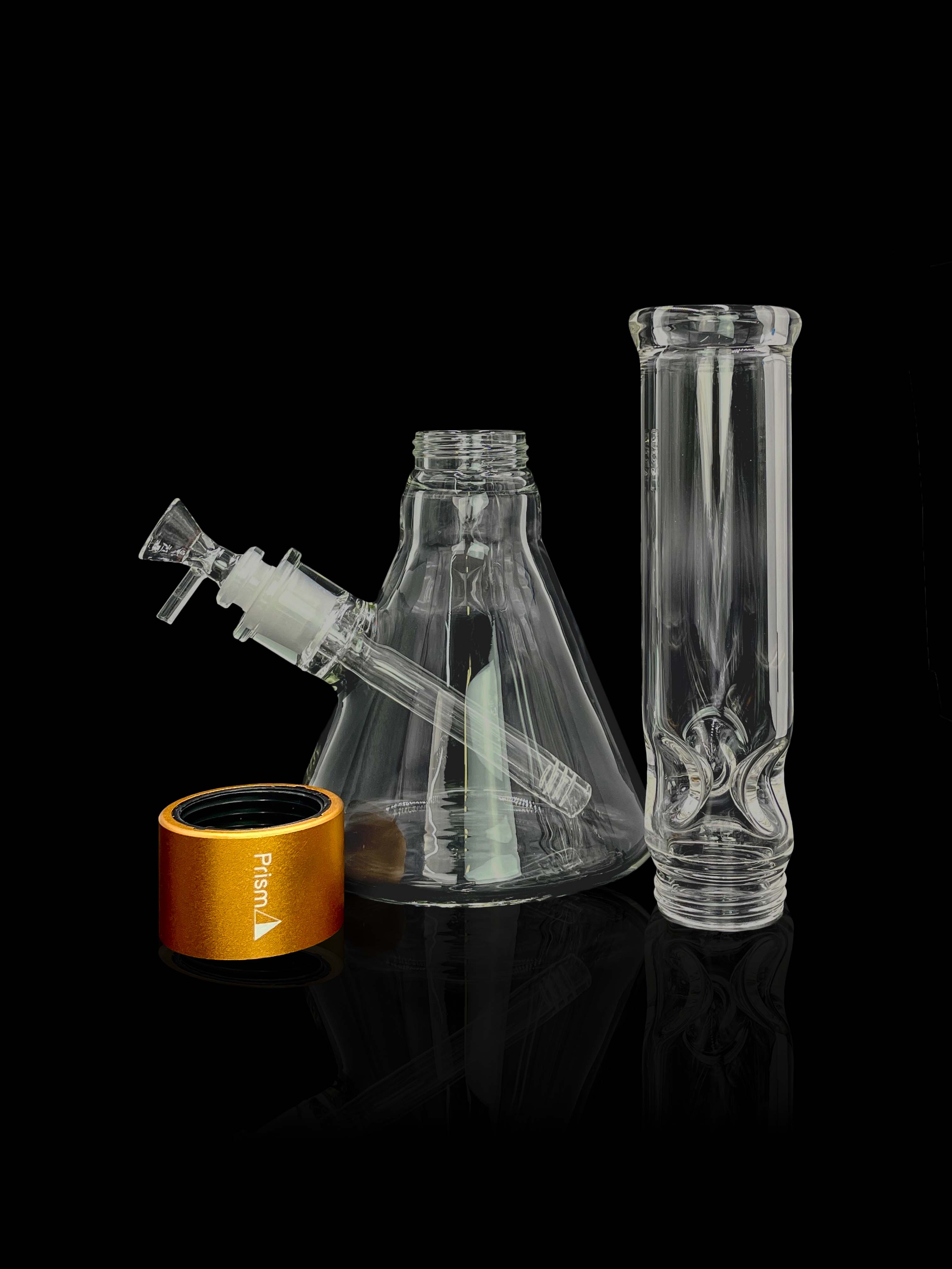 A front view of the Prism Water Pipes Starter Kit, displaying a clear glass pipe next to its branded packaging on a reflective black surface.