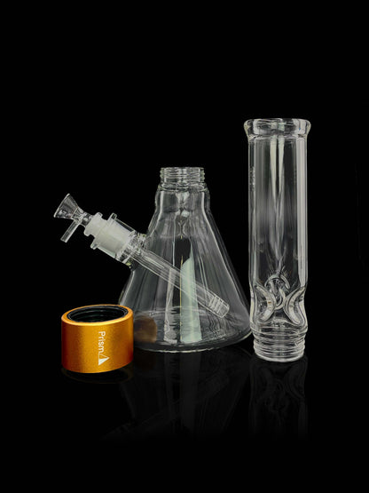 A front view of the Prism Water Pipes Starter Kit, displaying a clear glass pipe next to its branded packaging on a reflective black surface.