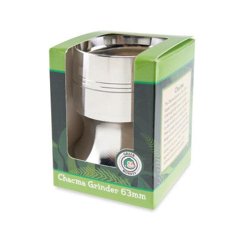 Angled front view of the Green Monkey Chacma Grinder with Ashtray in its green retail box, showing the silver 63mm grinder through a window.