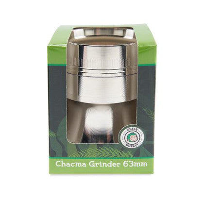 Front-facing shot of a silver Green Monkey Chacma Grinder with Ashtray 63mm visible through its green branded box window on a white background.