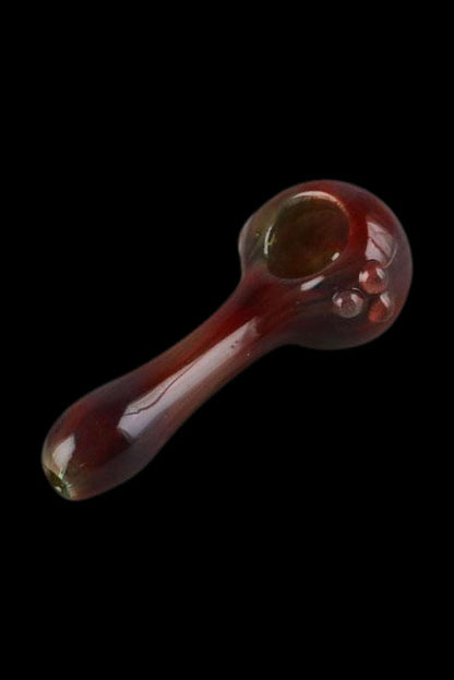 Red glass smoking pipe against a black background.