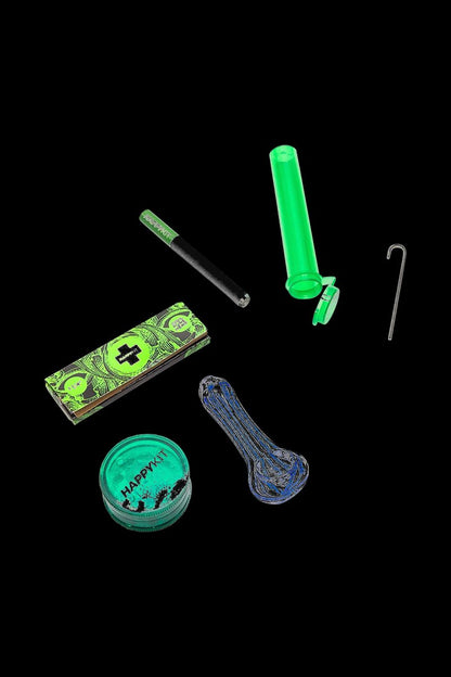 A cannabis kit featuring a glass pipe, rolling papers, a grinder, a metal dab tool, and a glass dab rig, all with a neon green glow, against a black background.