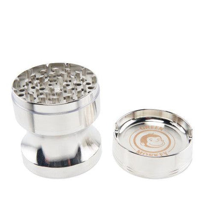 Studio-lit, three-piece view of the Green Monkey Chacma Grinder with Ashtray in polished silver showing teeth and branded ashtray insert