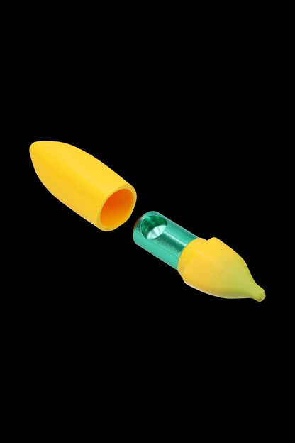 Diagonal close-up of the Metal Hand Pipe with Silicone Banana Skin showing its yellow silicone peel and green metal inner chamber against a black background